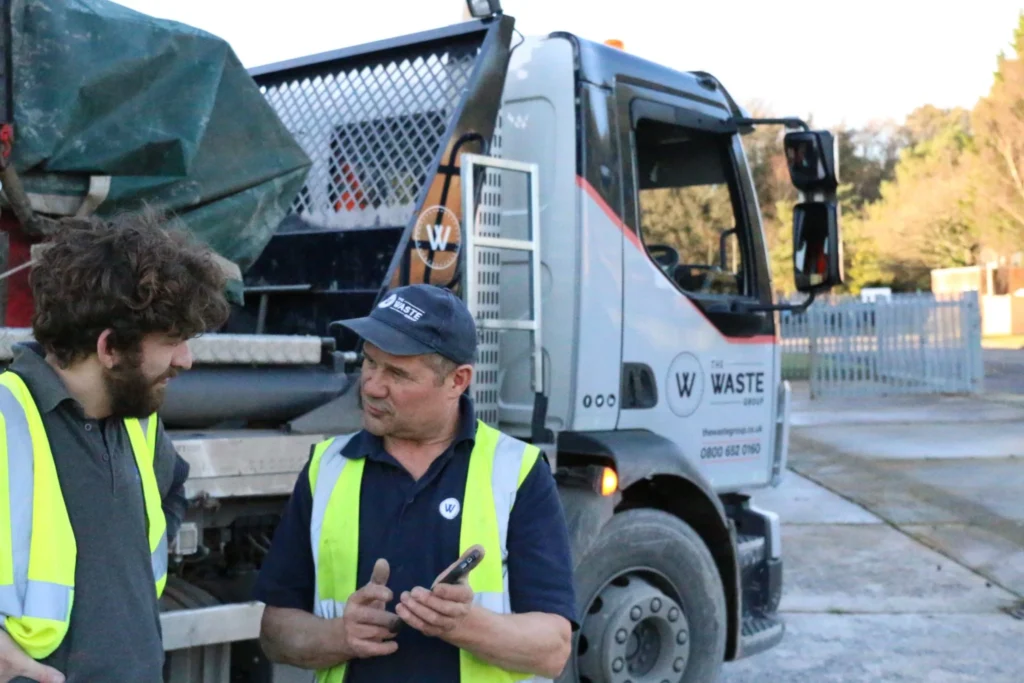 two waste group employees standing in front of a lorry and talking