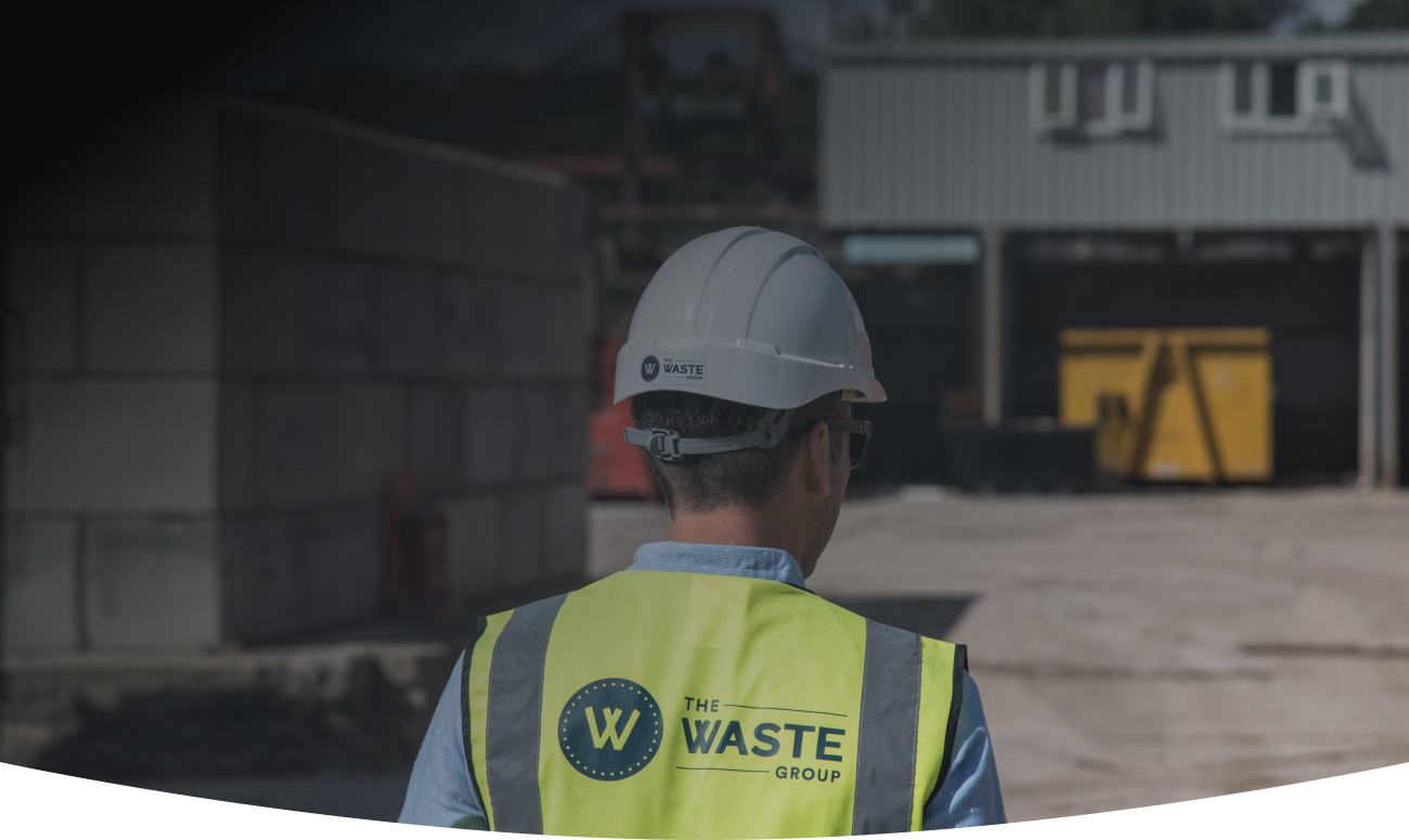 a waste group employee wearing a helmet and a vest with a logo on the back