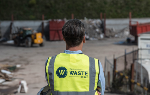 a man wearing a vest with the waste group logo on his back