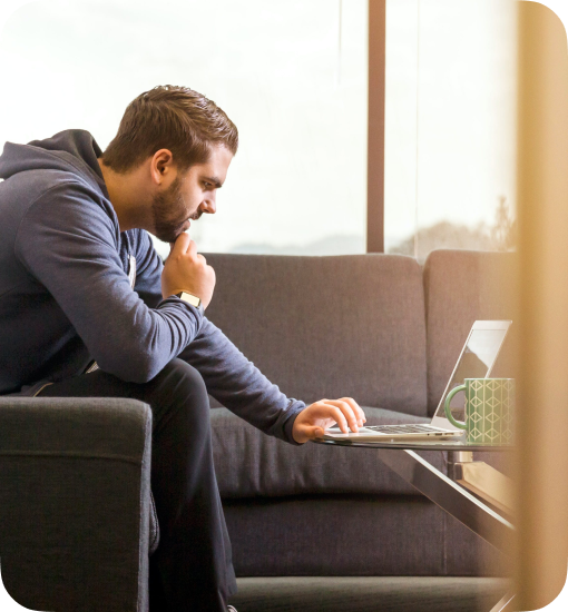 man sitting on a couch and typing on laptop