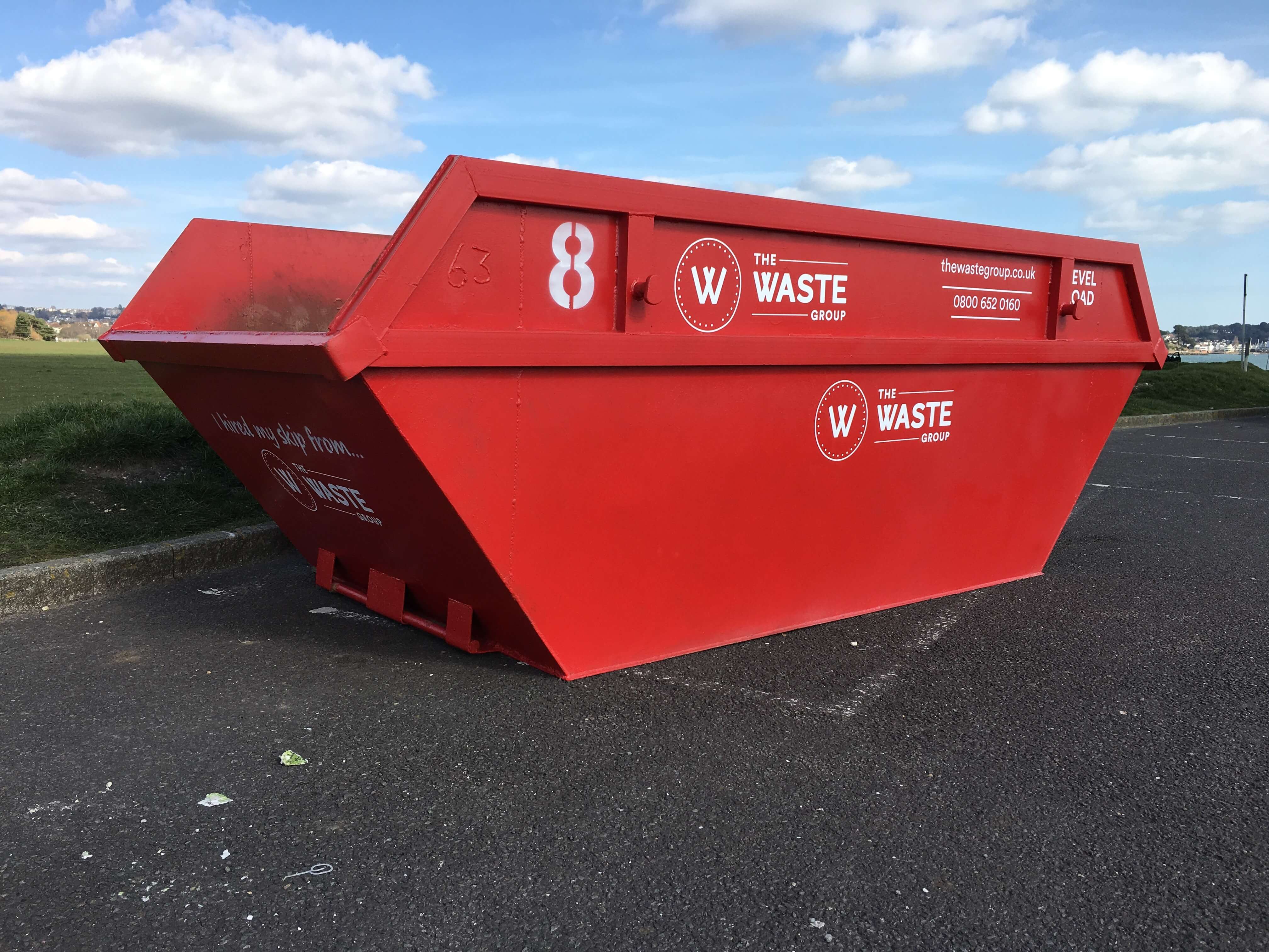 a red skip poole with the waste group logo