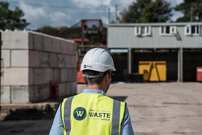 a construction worker wearing a vest with the waste group logo